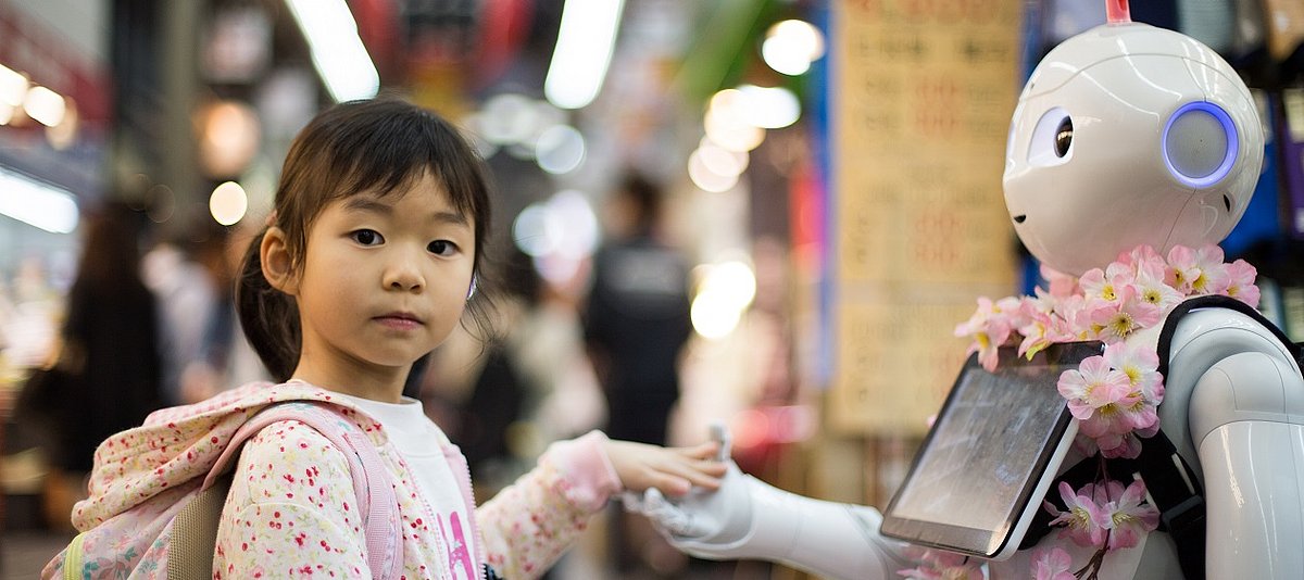 Ein Kind gibt einem Roboter die Hand
