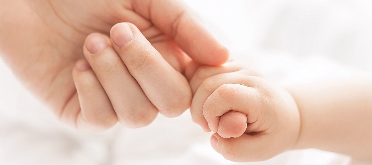 Babyhand umschließt einen Erwachsenenfinger
