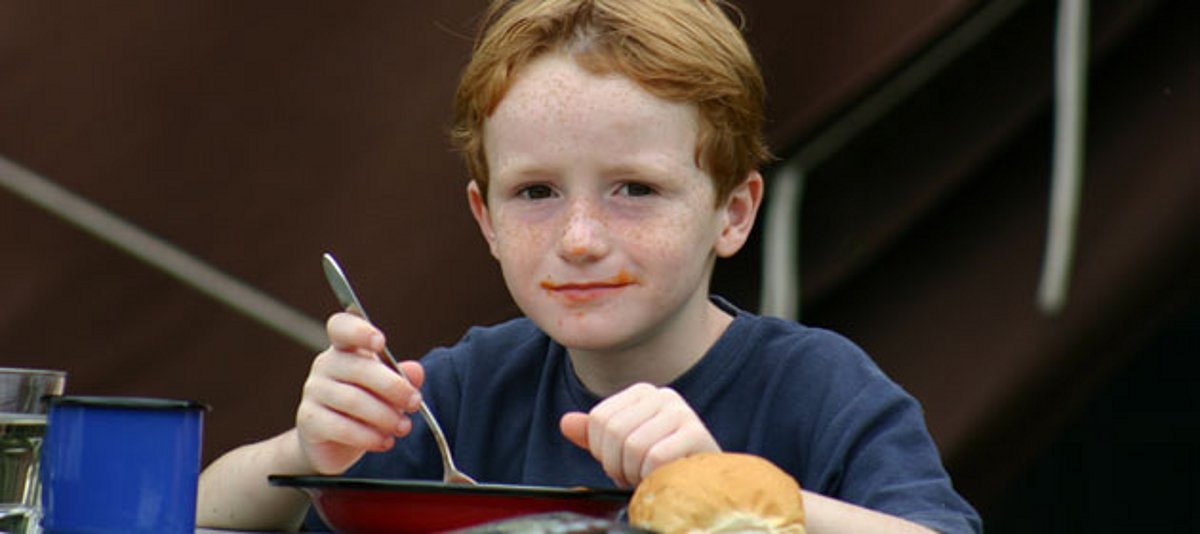 Ein Junge isst einen Teller Suppe