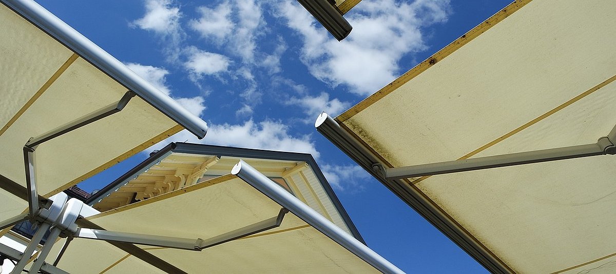 Vier ausgefahrene Sonnenschutzmarkisen vor heiterem Himmel