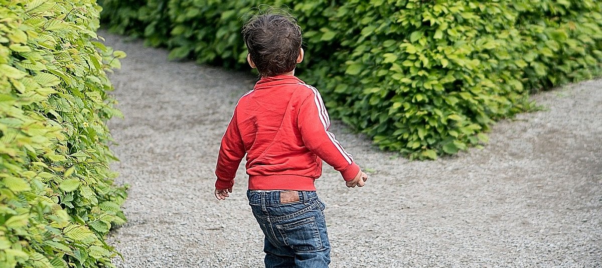 Ein kleiner Junge sucht alleine den Weg aus einem Irrgarten heraus
