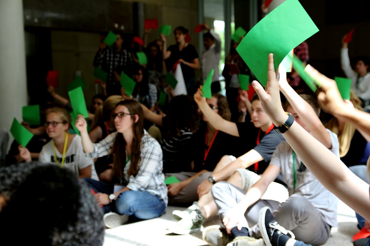 Teilnehmende sitzen auf dem Fußboden und stimmen ab. Foto vom Jugend-Landtag in 2015.