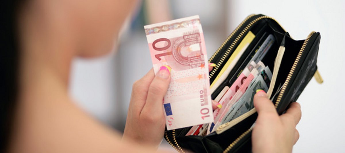 Frau holt 10 Euro Schein aus Portemonnaie