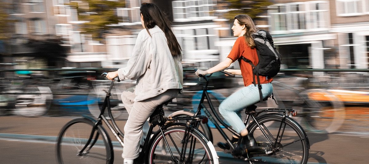 Zwei junge Frauen fahren auf Fahrrädern durch die Stadt