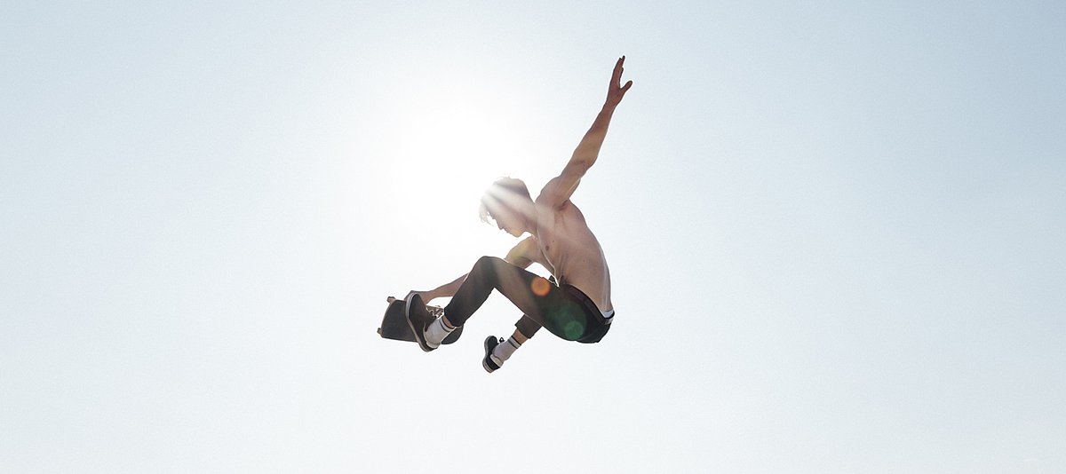 Junger Mann mit Skateboard in der Luft