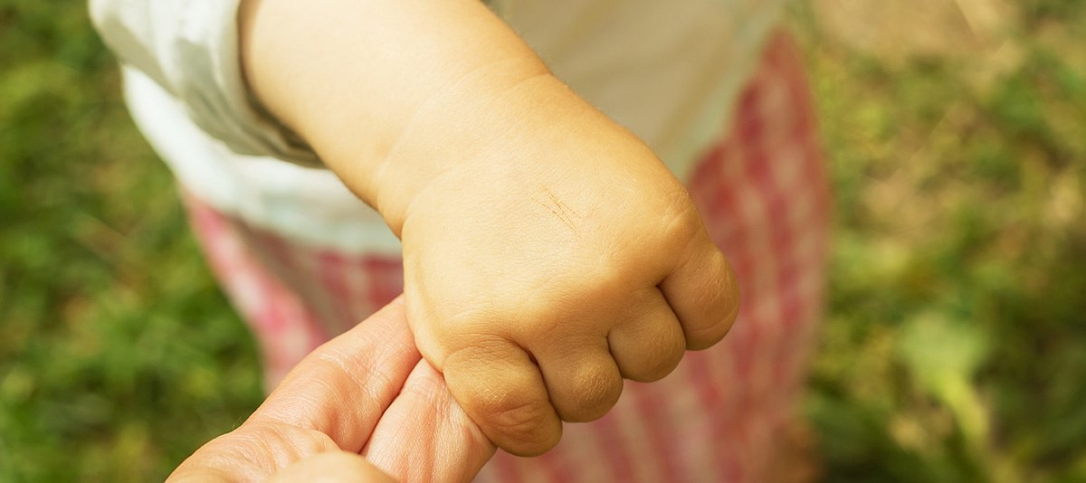 Erwachsener hält Kinderhand