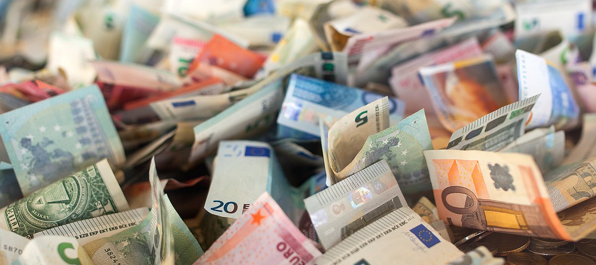 Euro und Dollarscheine auf Geldmünzen