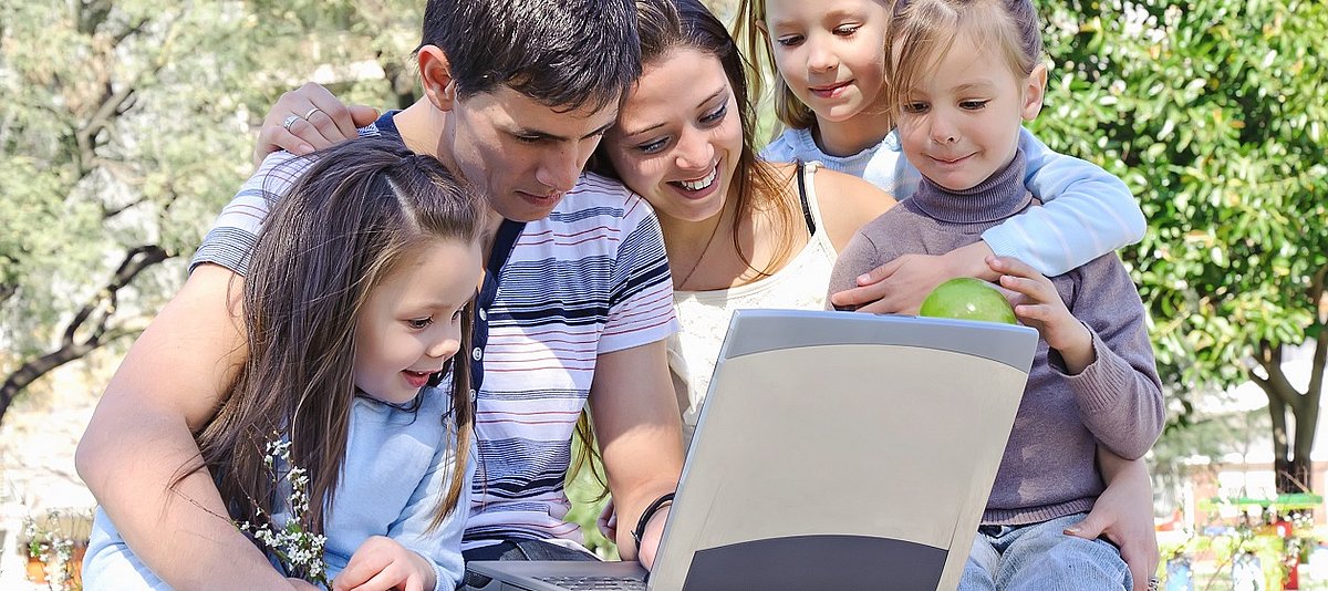 Eine Familie mit drei Kindern sind gemeinsam vor dem Computer.
