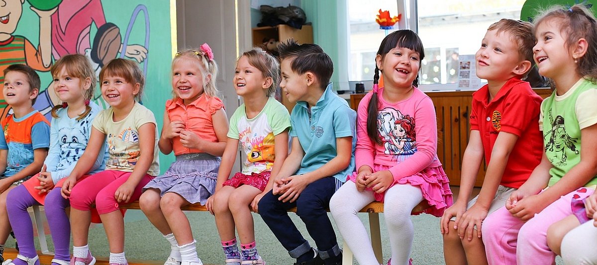 Kindergartenkinder sitzen lachend auf einer Bank