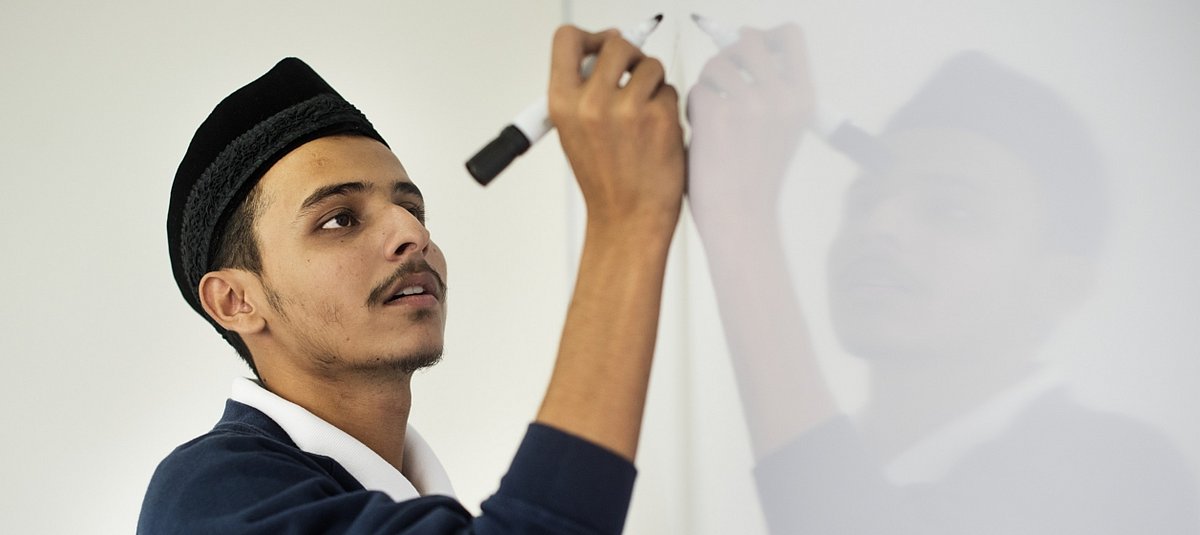 Junger Mann schreibt mit einem Stift auf einem Whiteboard