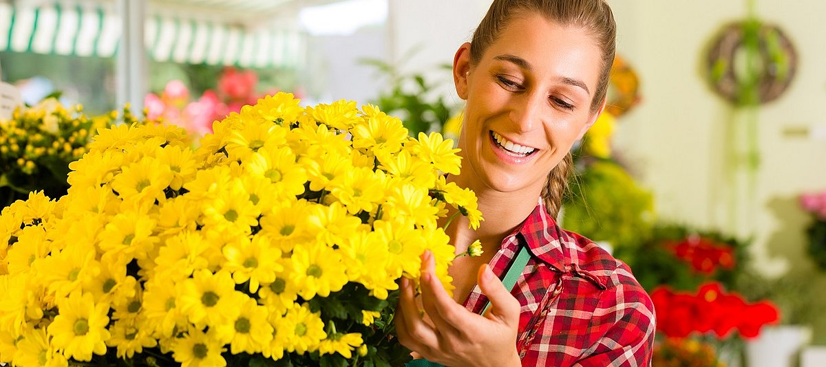 Verkäuferin zeigt einen gelben Blumenstrauß