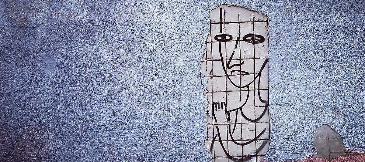 Streetart-Bild einer Person hinter Gitter auf einer Mauer