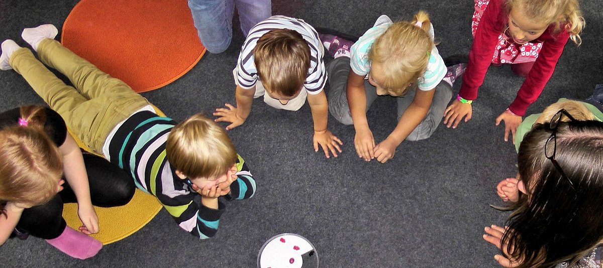 Eine Gruppe von Kindern liegt auf dem Boden und beobachtet ein Spiel