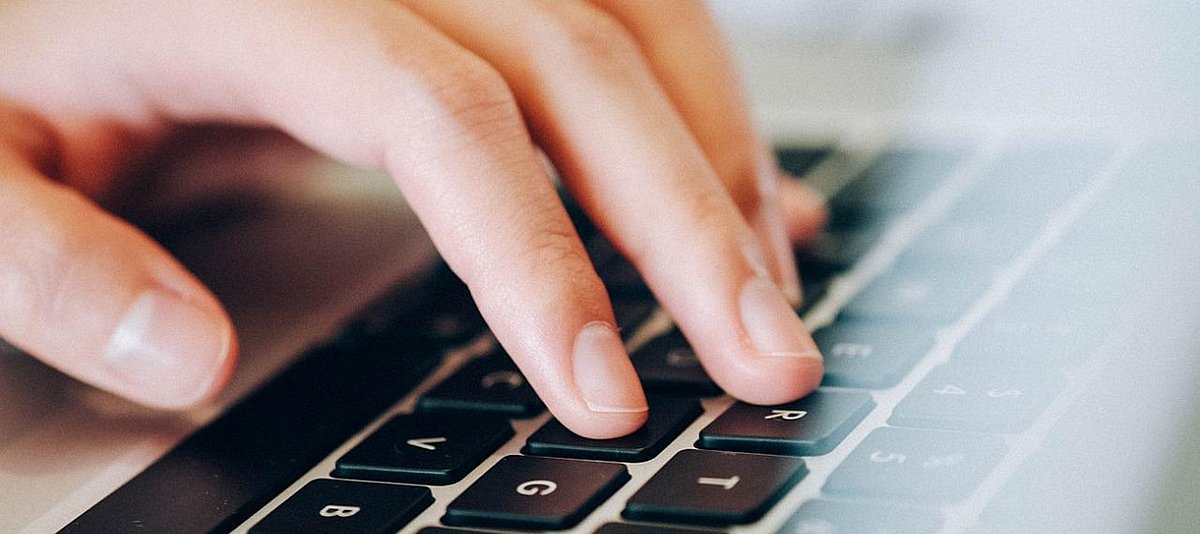 Eine Hand bedient die Tastatur eines Laptops.