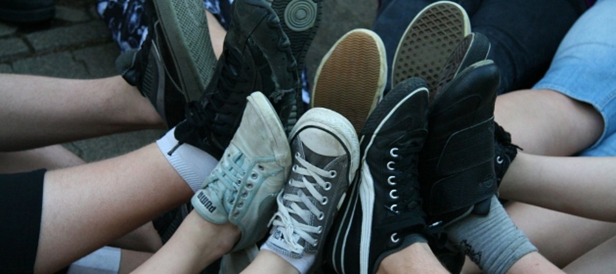 Mehrere Jugendliche halten ihre Schuhe aneinander.