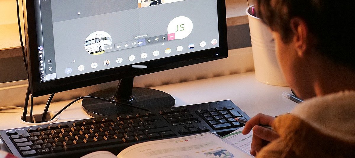 Ein Schüler sitzt im digitalen Unterricht am Computer.