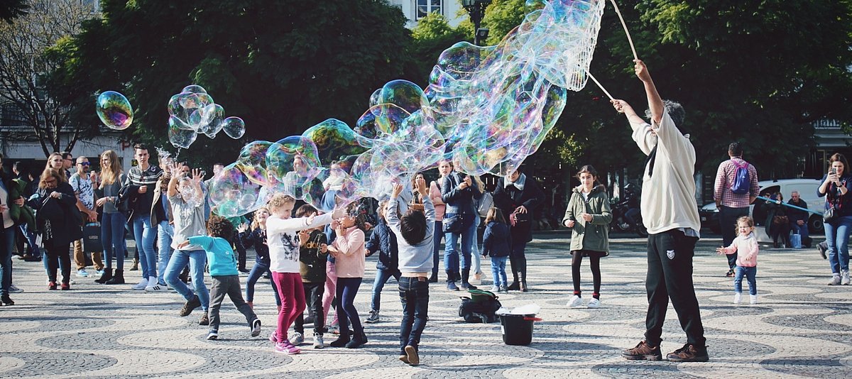 Kinder spielen mit großen Seifenblasen auf einem öffentlichen Platz
