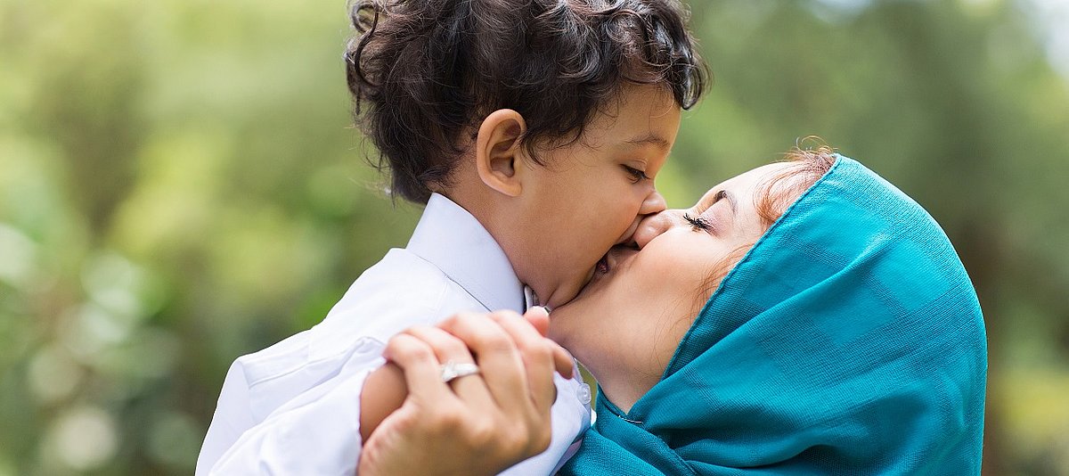 Ein Kleinkind bekommt einen dicken Kuss von seiner Mutter