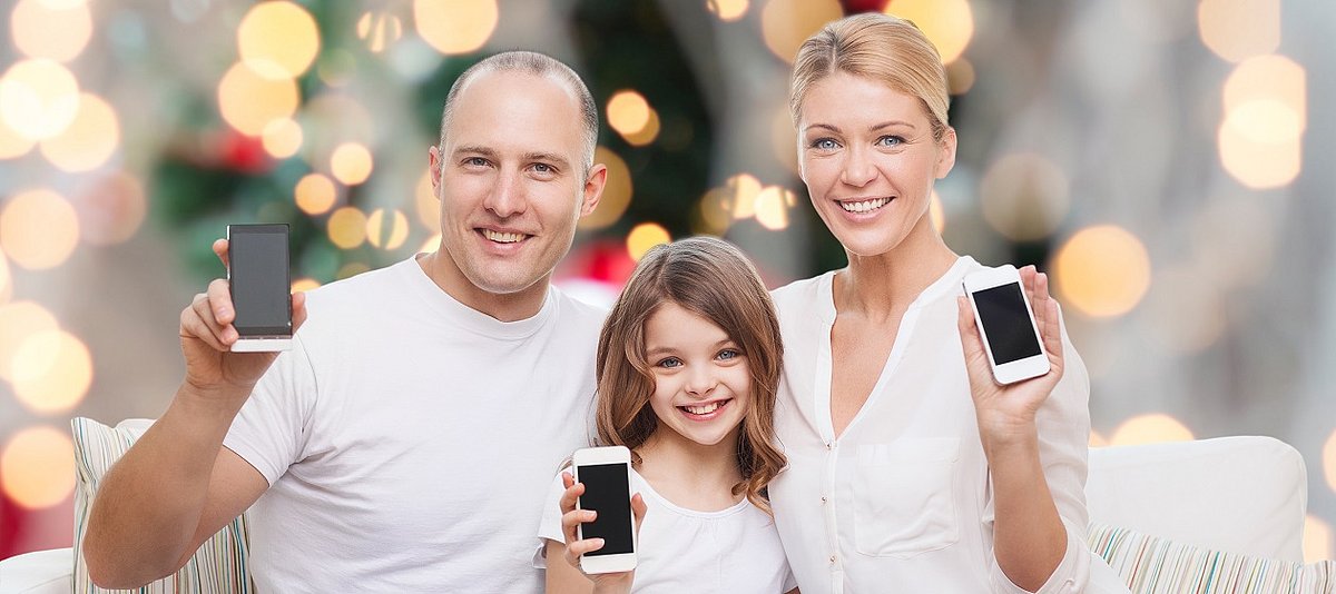 Vater, Mutter und Tochter halten gemeinsam ihre Smartphones in die Höhe