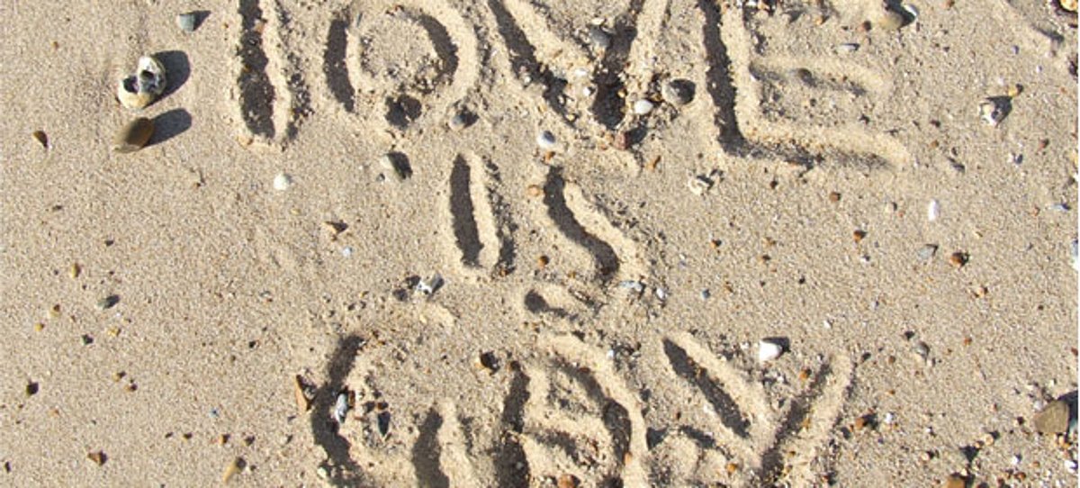 Schriftzug im Sand: love is gay