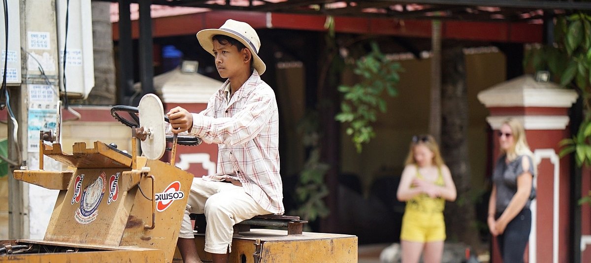 Ein kambodschanischer Junge sitze auf einem Straßenbaugerät und arbeitet