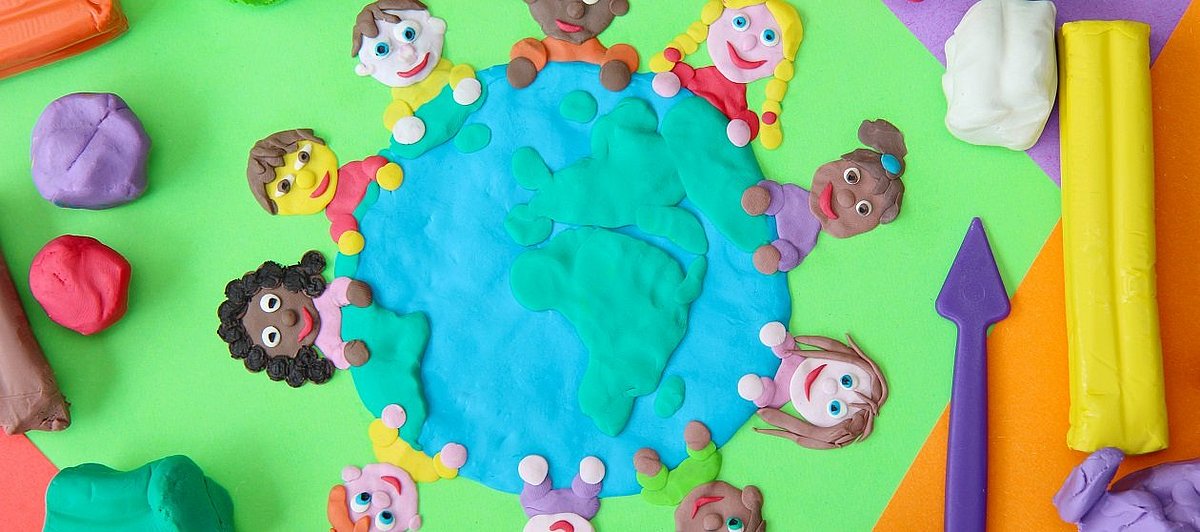 Sieben Kinder, aus Knete geformt, halten einen Globus fest