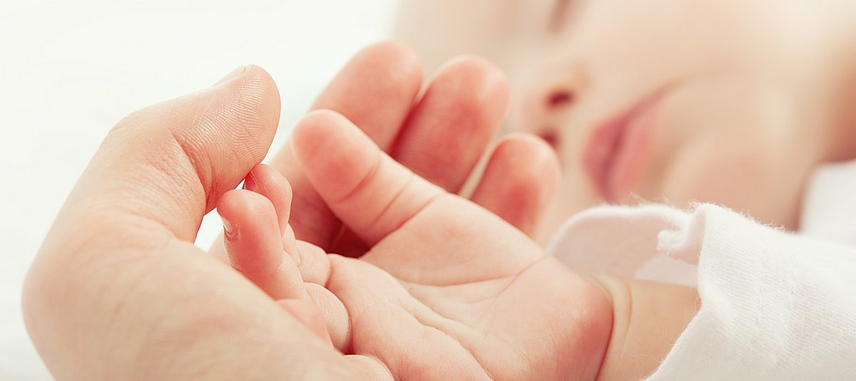 Die Hand eines Neugeborenen liegt in einer Erwachsenenhand