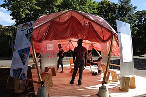 Jugendliche stehen in einem Zelt mit Ausstellungsbannern