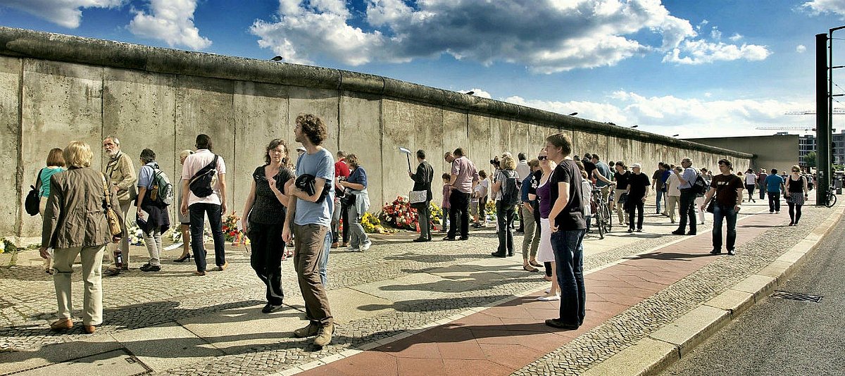 Viele Menschen stehen vor einem Teilstück der Berliner Mauer an der Bernauer Straße