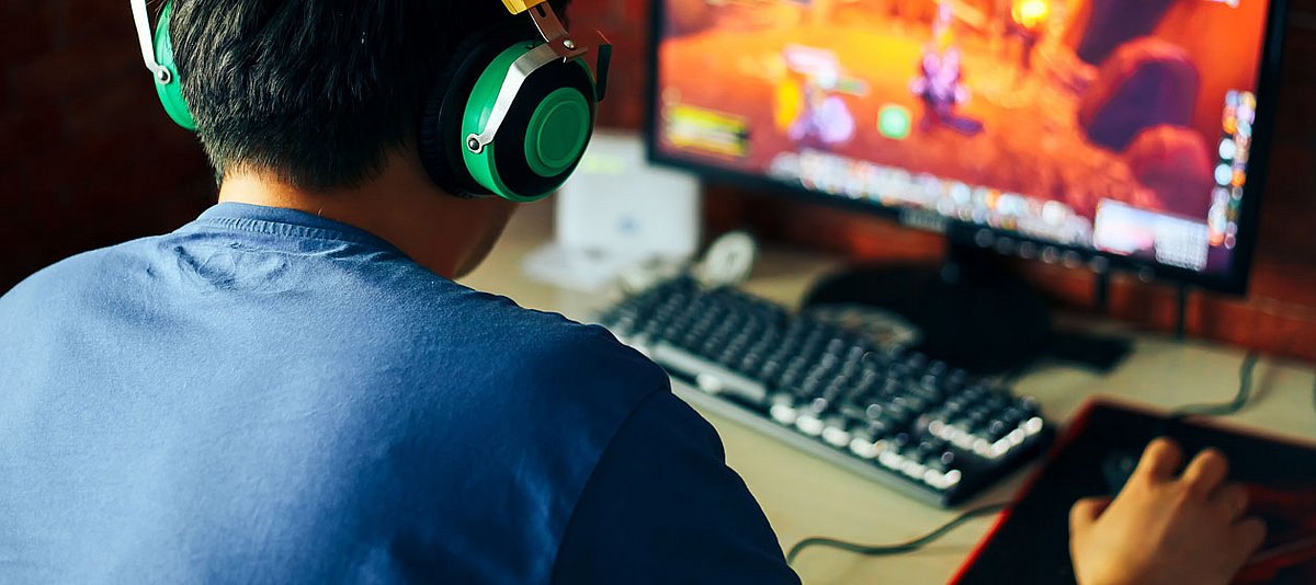 Ein Junge mit Kopfhörern spielt ein Computerspiel