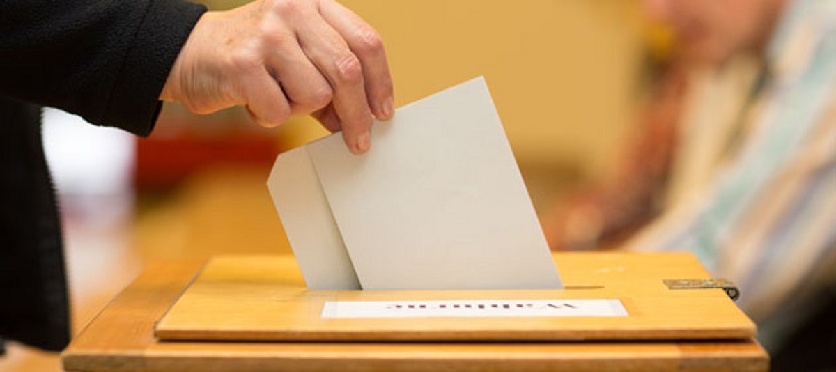 Zettel wird in Wahlurne gesteckt