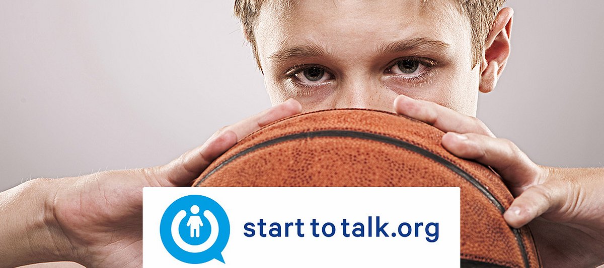 Ein Junge hält mit beiden Händen einen Basketball vor dem Gesicht, davor der Schriftzug "starttotalk.org"
