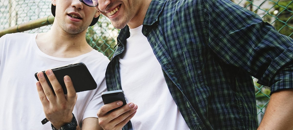 Zwei Jugendliche zeigen sich gegenseitig etwas auf ihren Smartphones