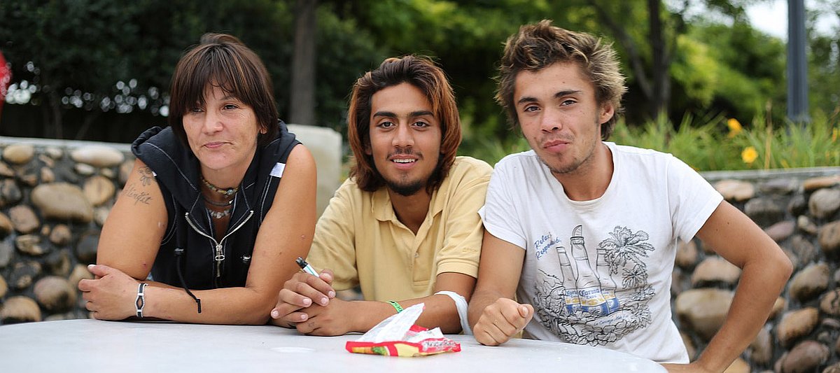 Drei junge Erwachsene sitzen an einem Gartentisch.