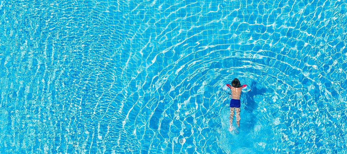 Ein Kind mit Schwimmflügeln schimmt in einem Schwimmbecken