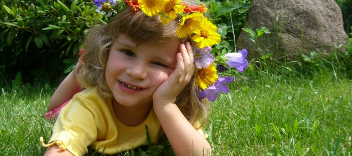 Ein Mädchen liegt auf der Wiese und trägt Blumen im Haar.