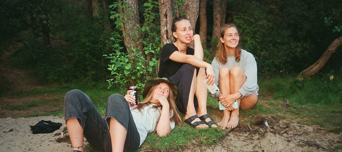 Drei junge Frauen sitzen vor einem Baum