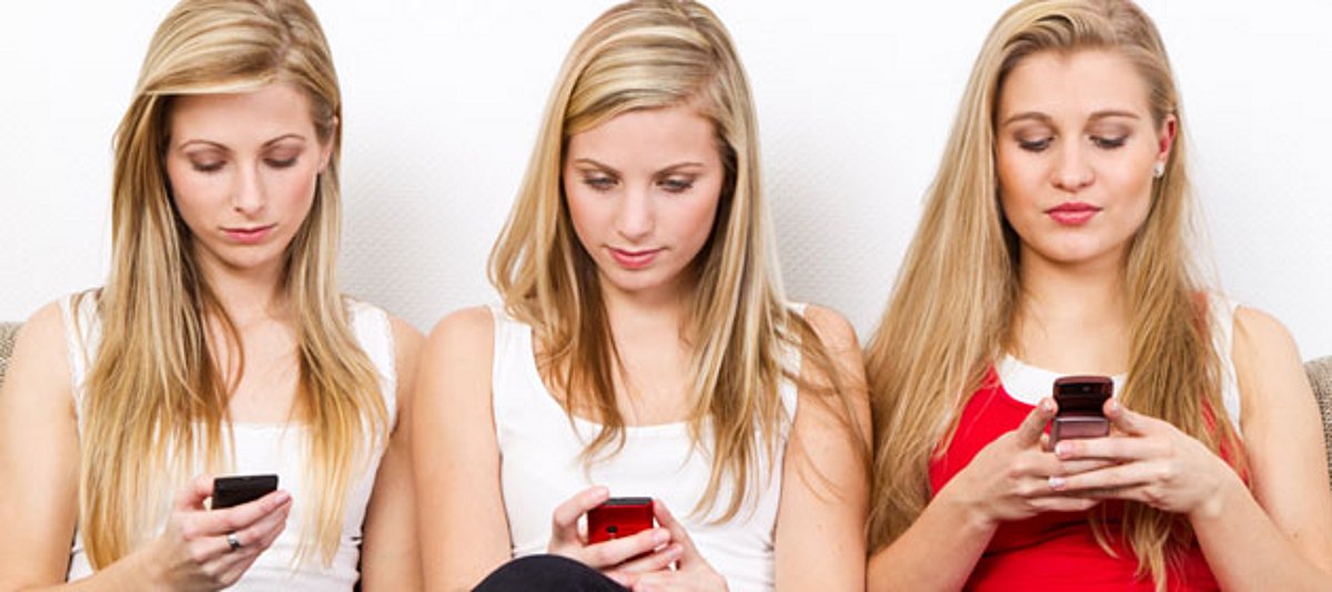 Drei junge Frauen spielen mit ihren Handys
