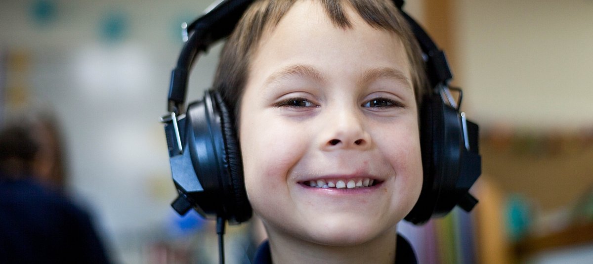 Kleinkind grinsend mit Kopfhörern