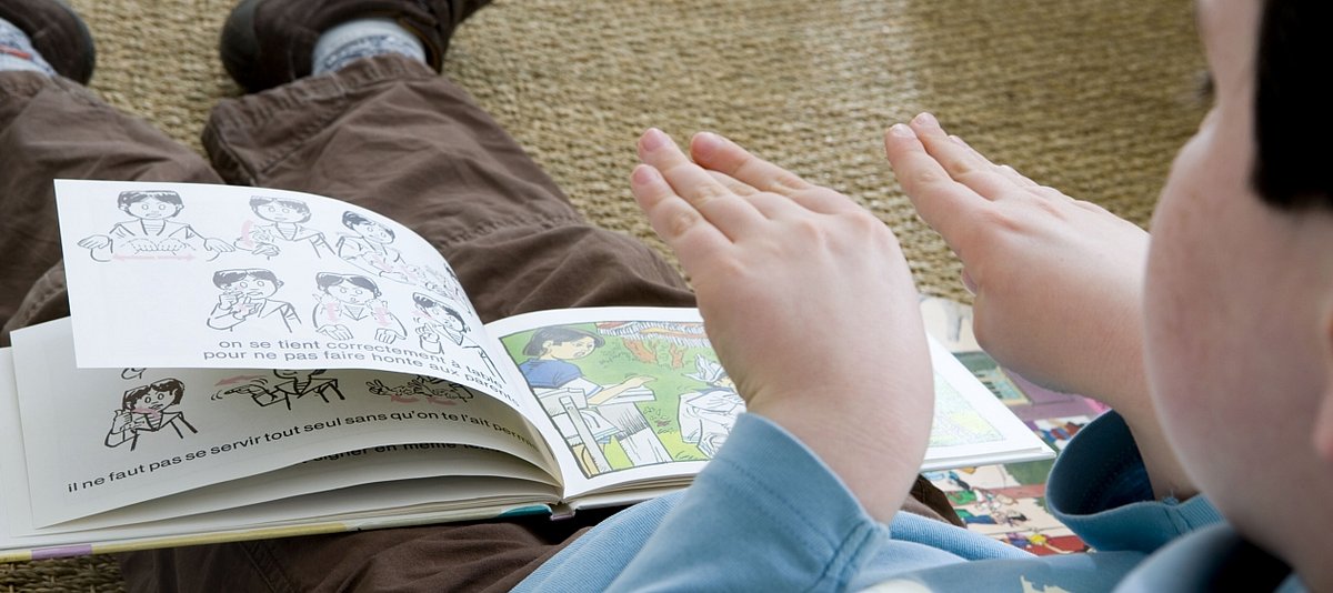 Kleiner Junge lernt Gebärdensprache mit Kinderbuch