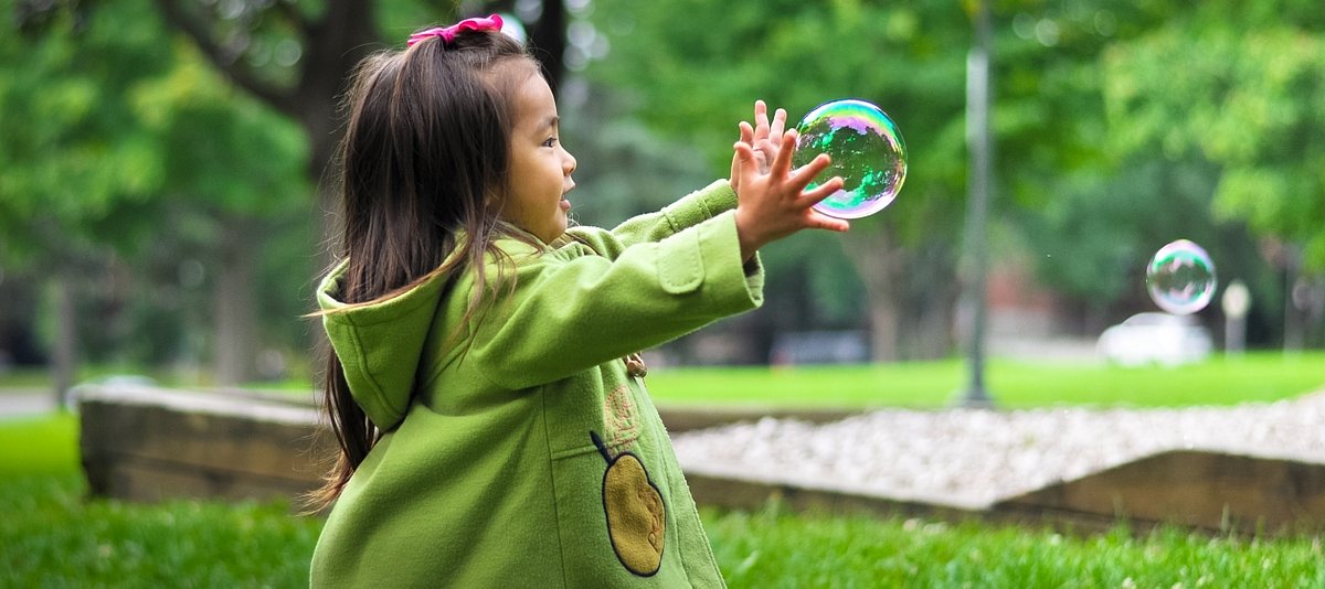 Ein kleines Mädchen spielt draußen mit Seifenblasen