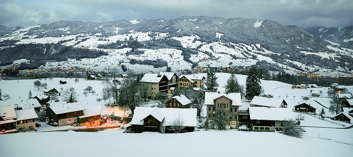 Ein verschneites Dorf in einer Mittelgebirgslandschaft