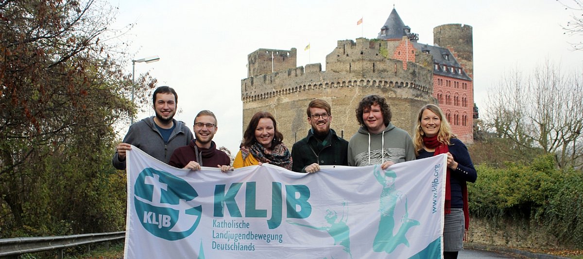 Die KLJB-Delegation hält ein Banner noch oben, im Hintergrund ist eine alte Burg zu sehen