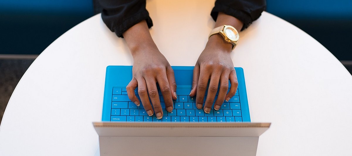 Nahaufnahme von Händer einer Person, die etwas auf dem Laptopm schreibt