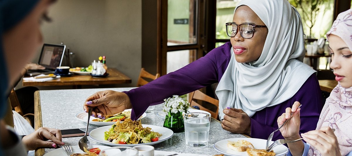Drei Frauen mit Kopftuch essen in einem Restaurant