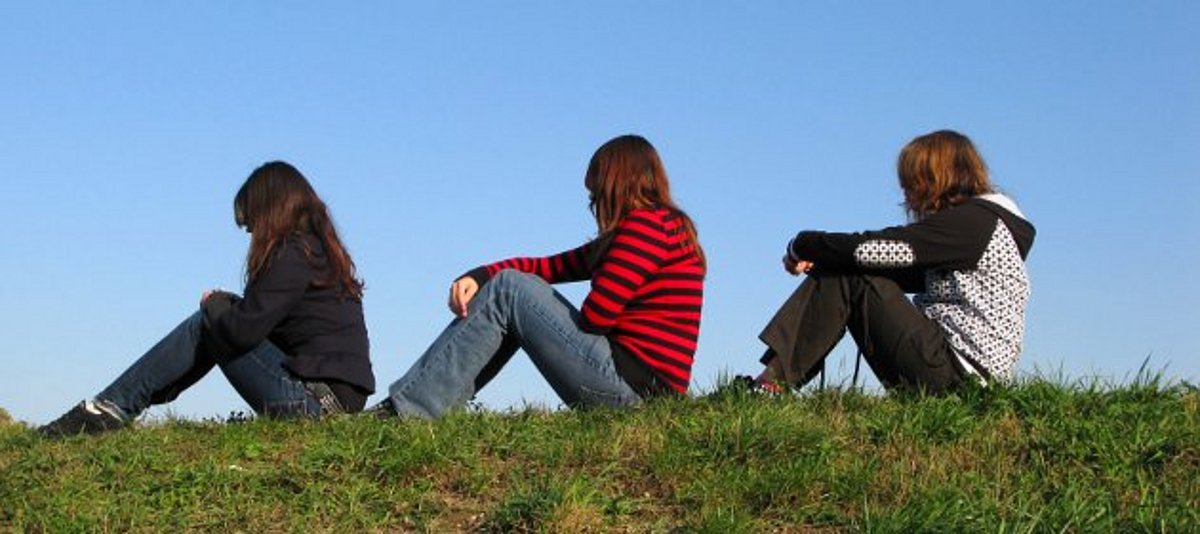 Drei Mädchen sitzen auf Wiese
