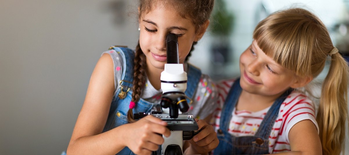 Zwei Mädchen betrachten etwas durch ein Mikroskop