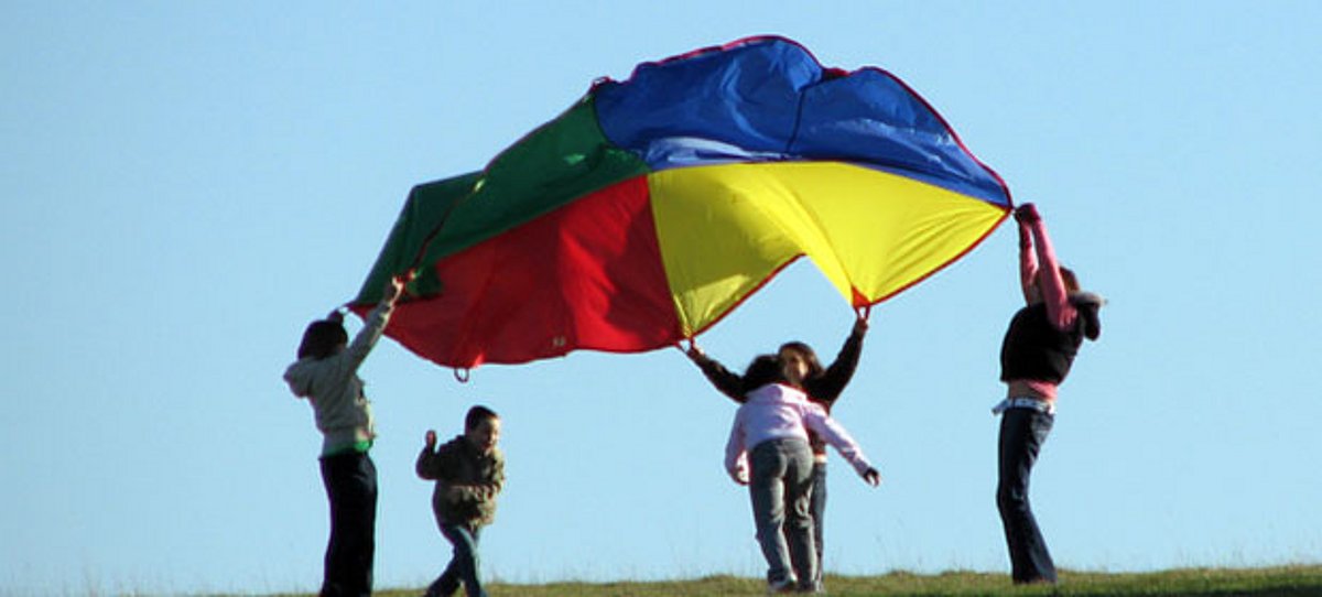 Jugendliche spielen mit einem Fallschirm
