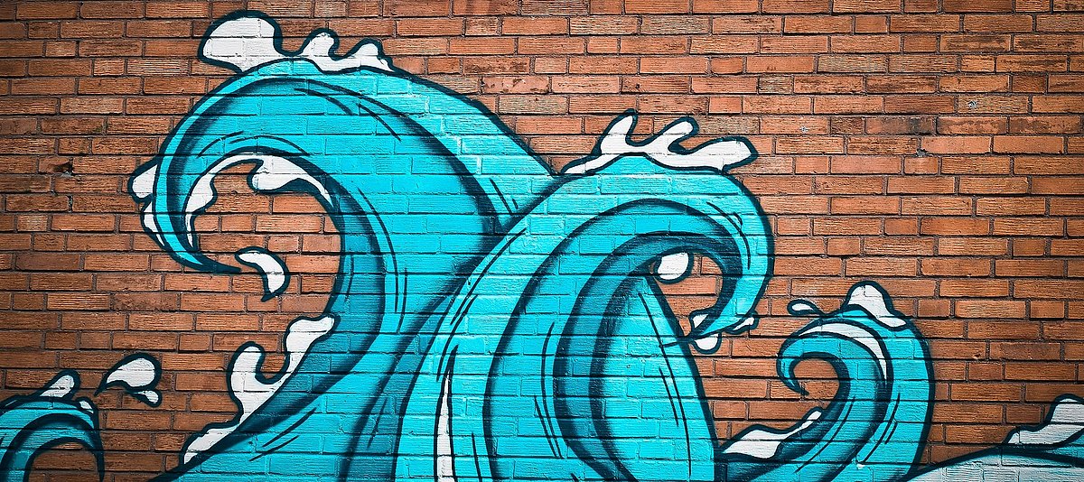 Ein Graffiti mit blauen Wellen an einer Backsteinmauer